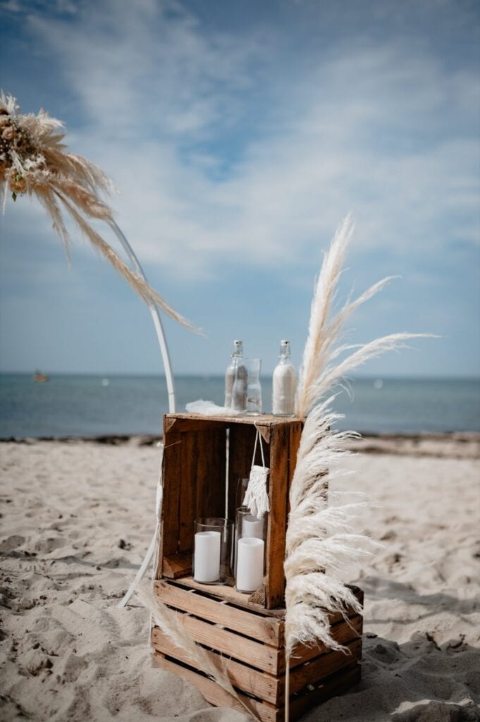 Dekoration mit Flaschen, Kerzen und Pampasgras am Strand.